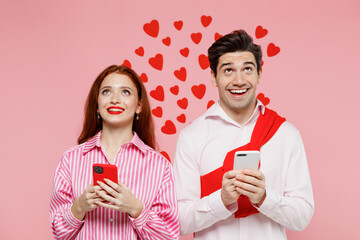 Wall Mural - Young couple two friends woman man in shirt using hold in hand mobile cell phone look overhead on workspace isolated on plain pastel pink background. Valentine's Day birthday holiday party concept