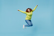 © ViDi Studio - Young overjoyed excited chubby overweight plus size big fat fit woman wear green sweater jump high with outstretched hands isolated on plain blue background studio portrait. People lifestyle concept.