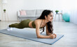 © Prostock-studio - Domestic training. Sporty Indian woman standing in plank yoga pose on mat at home, panorama