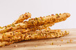 Grissini di pane ricoperti con granella di pistacchio e mandorle fotografati su un tagliere di legno
