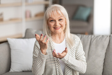 Wall Mural - Mature woman talking at camera gesturing and smiling