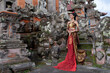 © Ace Mason - Beautiful balinese girl in traditional costume with a flower and a crown in her hair, and local temple