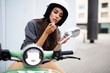 © Jelena - Beautiful woman getting ready for a ride on scooter. Young woman fixing up her makeup