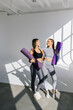 © F8  \ Suport Ukraine - Two athletic women friends in sportswear with yoga mats in sport class. Healthy lifestyle