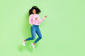 Wall Mural - Full length body size view of attractive cheerful lucky girl jumping showing copy space isolated on bright green color background