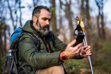 Image of hiker using phone while spending time in nature.	