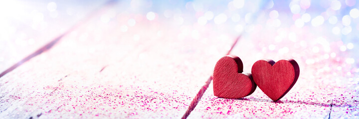 Wall Mural - valentines day - red wooden hearts on table with pink glitter and bokeh