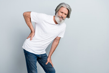 Portrait of attractive sad gray-haired man touching back suffering isolated over grey pastel color background