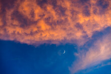 Crescent Moon Against Blue Sky With Pink And Orange Clouds