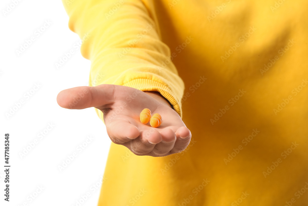 Young man with yellow earplugs on white background