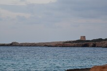 
The Sea, Rocks And An Old Tower In The Coast Of Ibiza