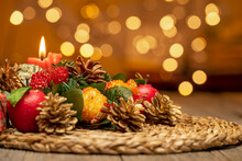 CHRISTMAS TABLE CENTERPIECE WITH RED CANDLE AND PINE CONES. BOKEH LIGHTS BACKGROUND. SELECTED FOCUS.