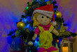 Lalka szmaciana w czapce Świętego Mikołaja . Choinka , bombki , lampki . Boże Narodzenie .