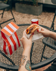 Hamburguesas gourmet en manos de una joven comiendo tranquilamente 