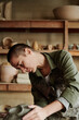 © AnnaStills - Young woman making form from the clay working at the table in ceramic studio