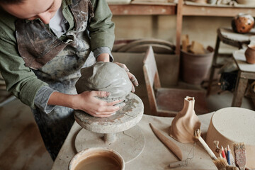 Wall Mural - Close-up of sculptor making human face from clay using special equipment in the workshop