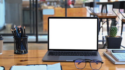 Fototapete - Laptop computer with white screen, pencil holder and calculator on wooden table.