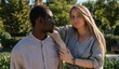 © anuatmoralesfoto - Shot of a beautiful blonde woman looking at the camera while leaning her arm on her african boyfriend that is looking away.