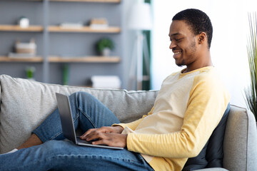 Happy black man enjoying his remote job, using laptop