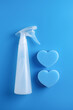 White spray bottle with antibacterial liquid and blue sponges on blue background. Cleaning concept.