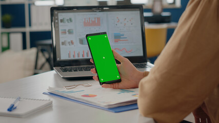 Poster - close up of adult vertically holding phone with green screen in startup office. business woman using