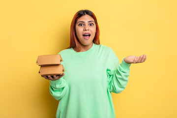 hispanic woman feeling happy and astonished at something unbelievable. take away burgers concept