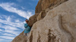 The wall of the ancient Egyptian pyramid of Cheops. Close-up. A man is standing on huge boulders, holding onto a stone and smiling. Blue sky with picturesque clouds.