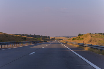 highway road in the countryside, roadside and asphalt, green forest and blue sky on a sunny day