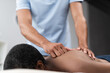 blurred physiotherapist doing back massage to african american man during rehabilitation treatment