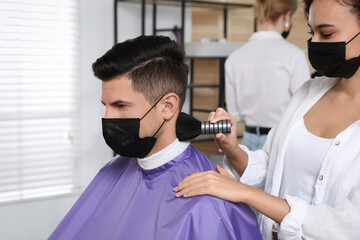 Canvas Print - Professional stylist working with client in salon. Hairdressing services during Coronavirus quarantine