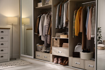 wardrobe closet with different stylish clothes, shoes and home stuff in room