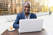 © ADDICTIVE STOCK - Cheerful black businessman working on computer with coffee in cafe
