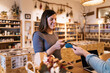© ADDICTIVE STOCK - Pregnant female paying with smartphone in eco friendly store