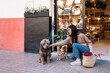 © ADDICTIVE STOCK - Positive female squatting down and stroking dog on street in daytime