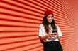 © VISTA by Westend61 - Smiling woman using mobile phone at red corrugated wall