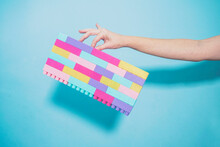 Arm Of Woman Holding Colorful Pastel Colored Toy Blocks Against Blue Background