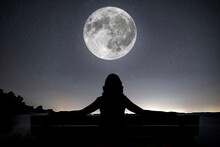 Image Of Silhouette Sitting On A Bench Looking At A Shinning Full Moon.