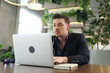© FotoArtist - Portrait of young man sitting at his desk using laptop in the office.