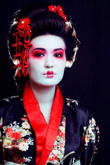 Wall Mural - young pretty real geisha in kimono with sakura and decoration on black background