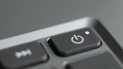 Turning on the laptop. The finger presses the start button on the computer. 