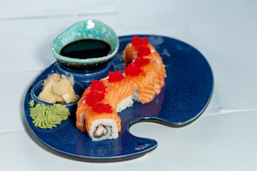 Wall Mural - sushi roll dragon philadelphia decorated with red caviar in a blue plate on a white background
