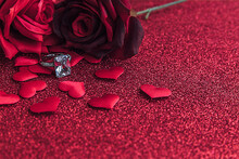 Will You Marry Me. Wedding Ring Red Scarlet Roses And Many Red Hearts On Red Glitter Background. Engagement Marriage Proposal Wedding Concept. St. Valentine's Day Postcard. Banner On Valentines Day