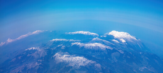 Wall Mural - Curvature of planet earth. Aerial view. Blue sky over snowed mountain peaks. Space, science concept