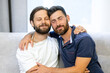 © Ivan - Adorable smiling young LGBT couple sharing a special moment together sitting on the sofa in the living room cuddling