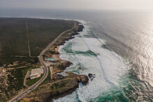 Aerial View Of Vehicles Driving A Scenic Road Along The Wild Coastline Near The Ocean, Cascais, Lisbon, Portugal.