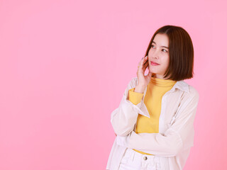 Portrait studio cutout shot Asian young pretty short hair female stylish model in yellow long sleeve shirt and jacket stand smile look at camera hold hand point up blank copy space on pink background