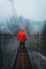 Back View Of A Person In Red Jacket Walking The Rope Bridge During Daytime