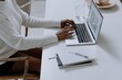 © Scopio - Cropped image of Black woman working on a laptop on light desk