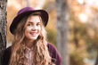 © Scopio - Portrait of smiling teenage girl with purple hat standing beside tree