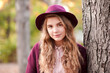 © Scopio - Portrait of teenage girl with purple hat standing beside tree